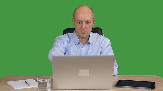 在透明的绿色背景下商人在办公室的笔记本电脑上工作视频的预览图