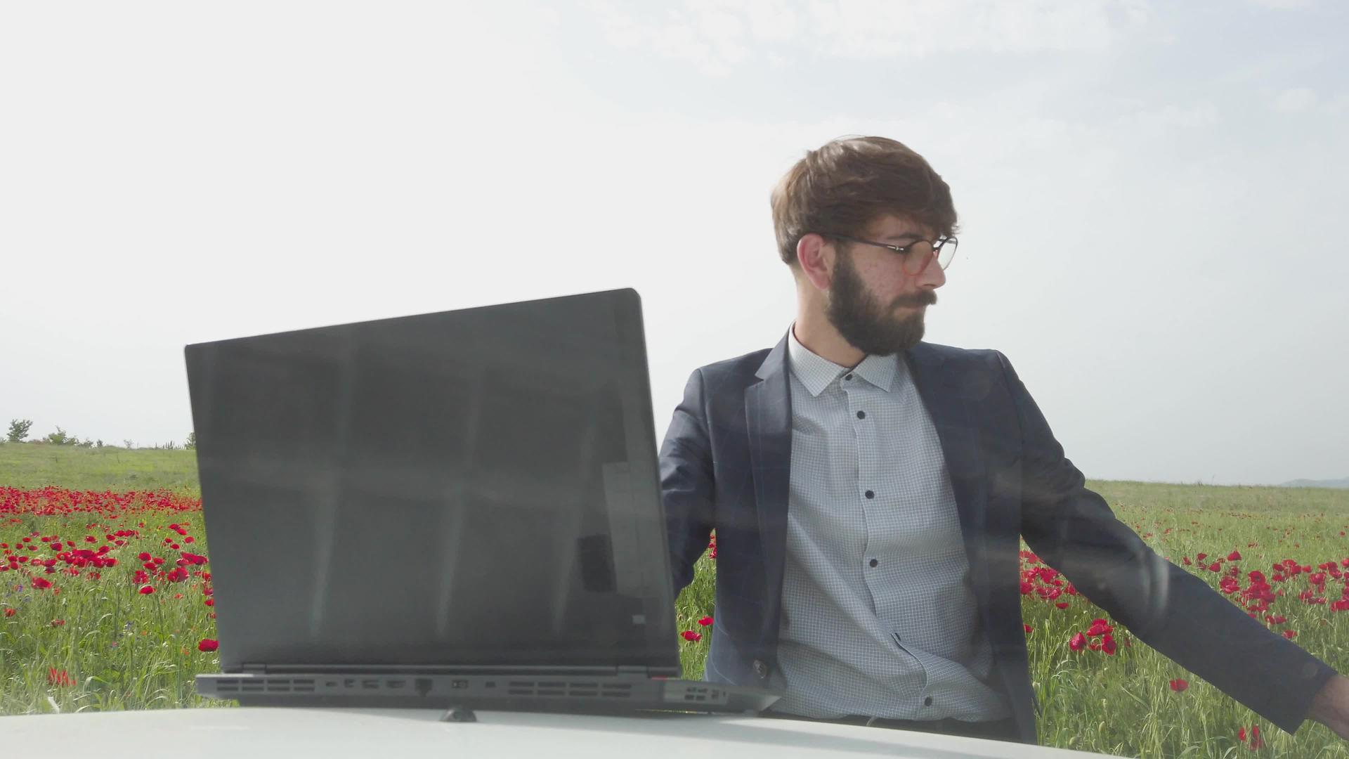 商人在一辆车里拿着笔记本电脑在红色的郁金香田里视频的预览图
