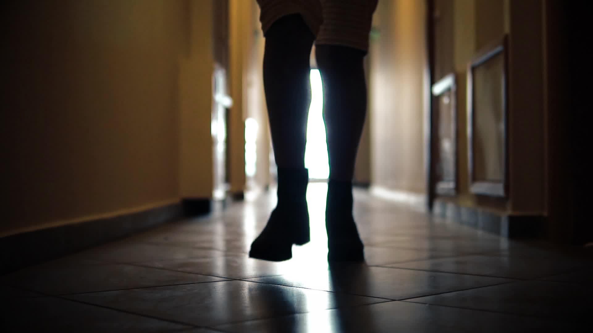 穿着靴子的女人双腿平滑缓缓地在走廊里跑着视频的预览图