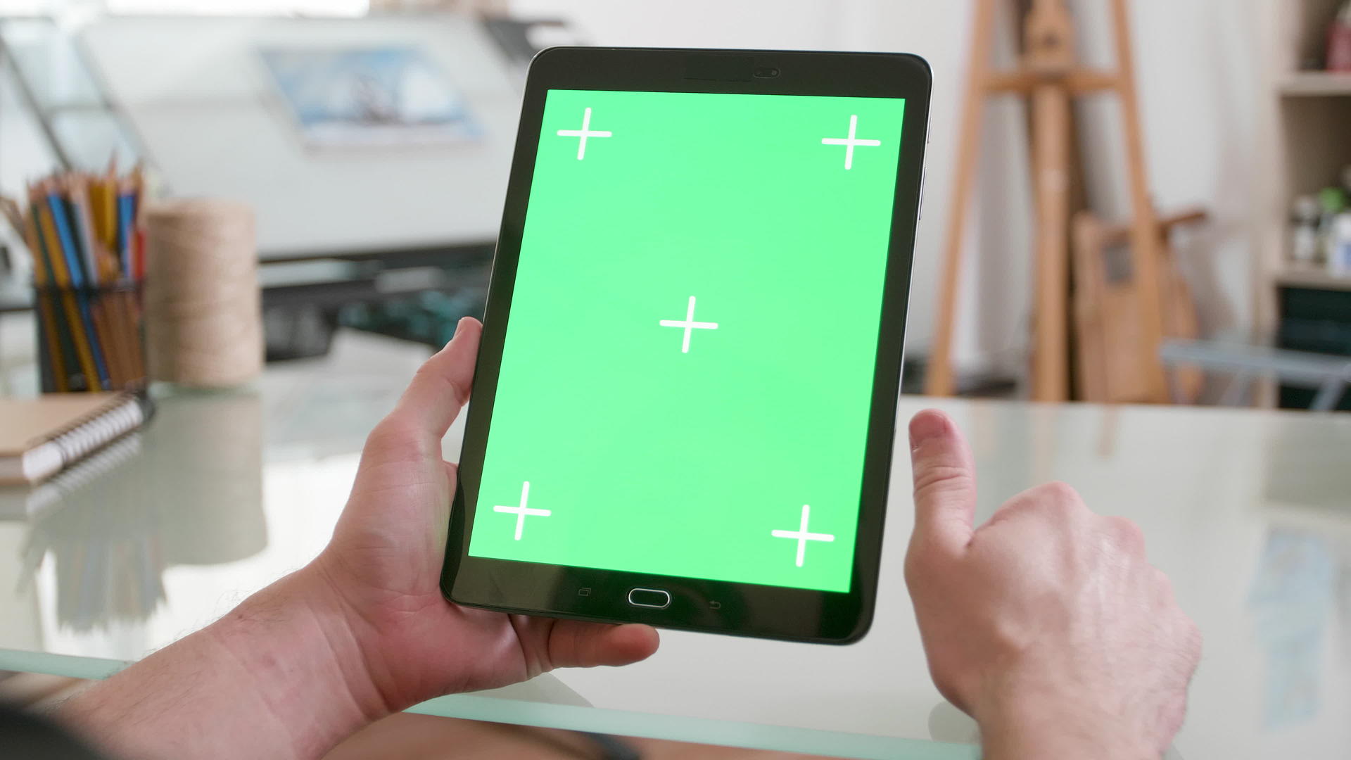 男人手里拿着一台黑色的平板电脑双手戴着绿色的屏幕不停地看着视频的预览图