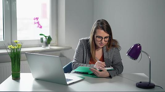 在办公室用笔记本电脑工作的年轻女商人或经理视频的预览图
