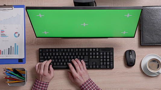 男性手在绿屏监视器前键盘上打字视频的预览图