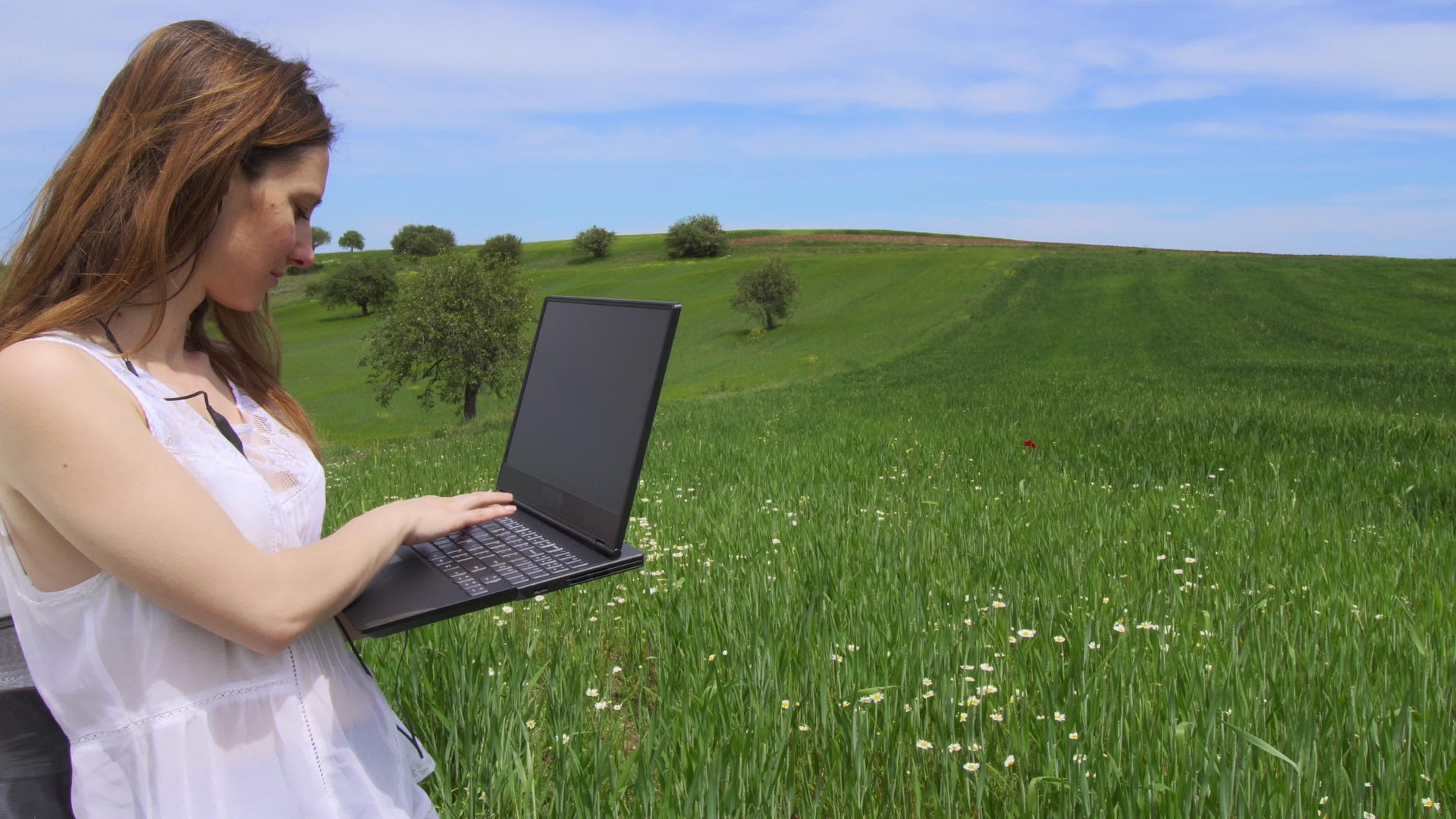 独自在绿色的田野里使用笔记本电脑视频的预览图