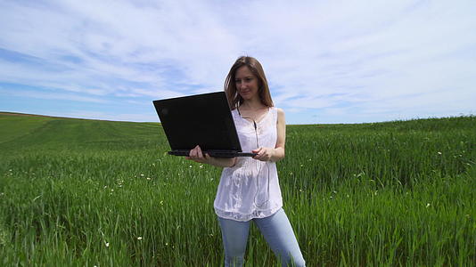 白发女孩独自站在绿色的田野里有笔记本电脑、自由商业和自由商业视频的预览图