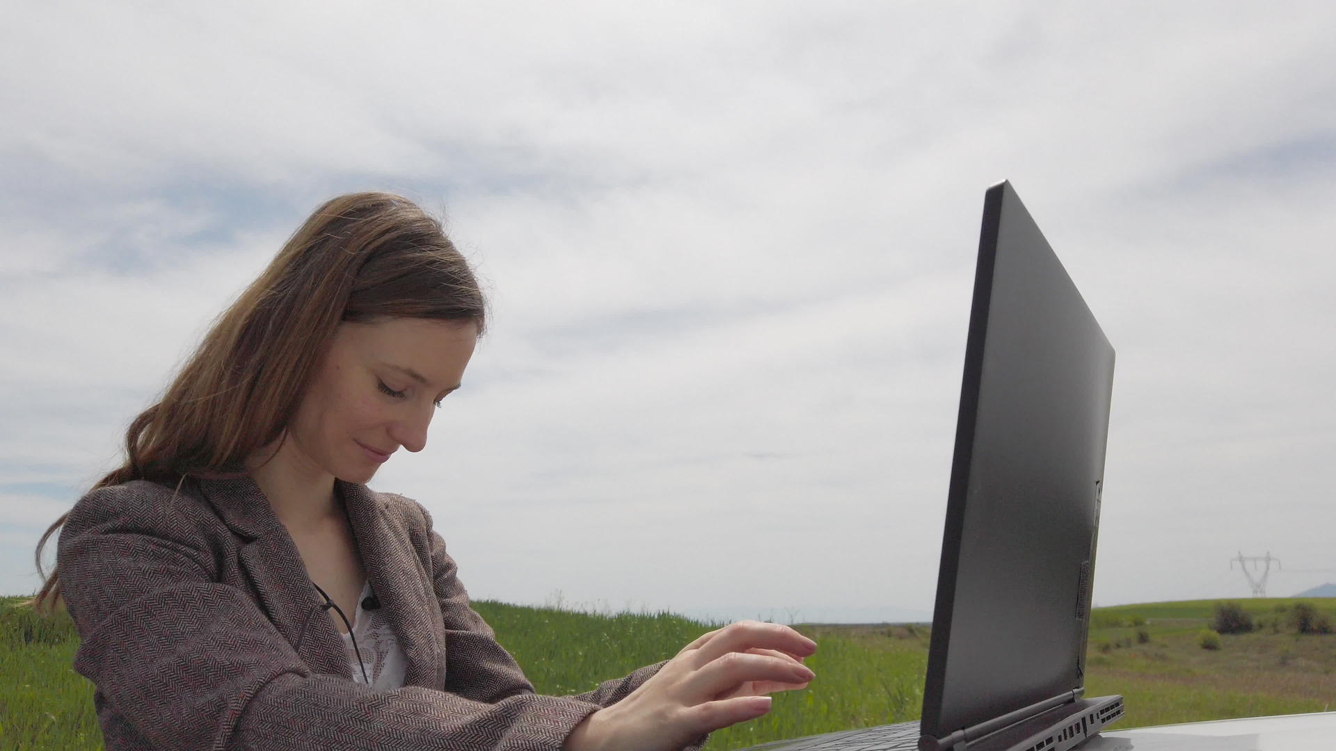 车上有一台笔记本电脑的女商人独自在绿色的田野里视频的预览图