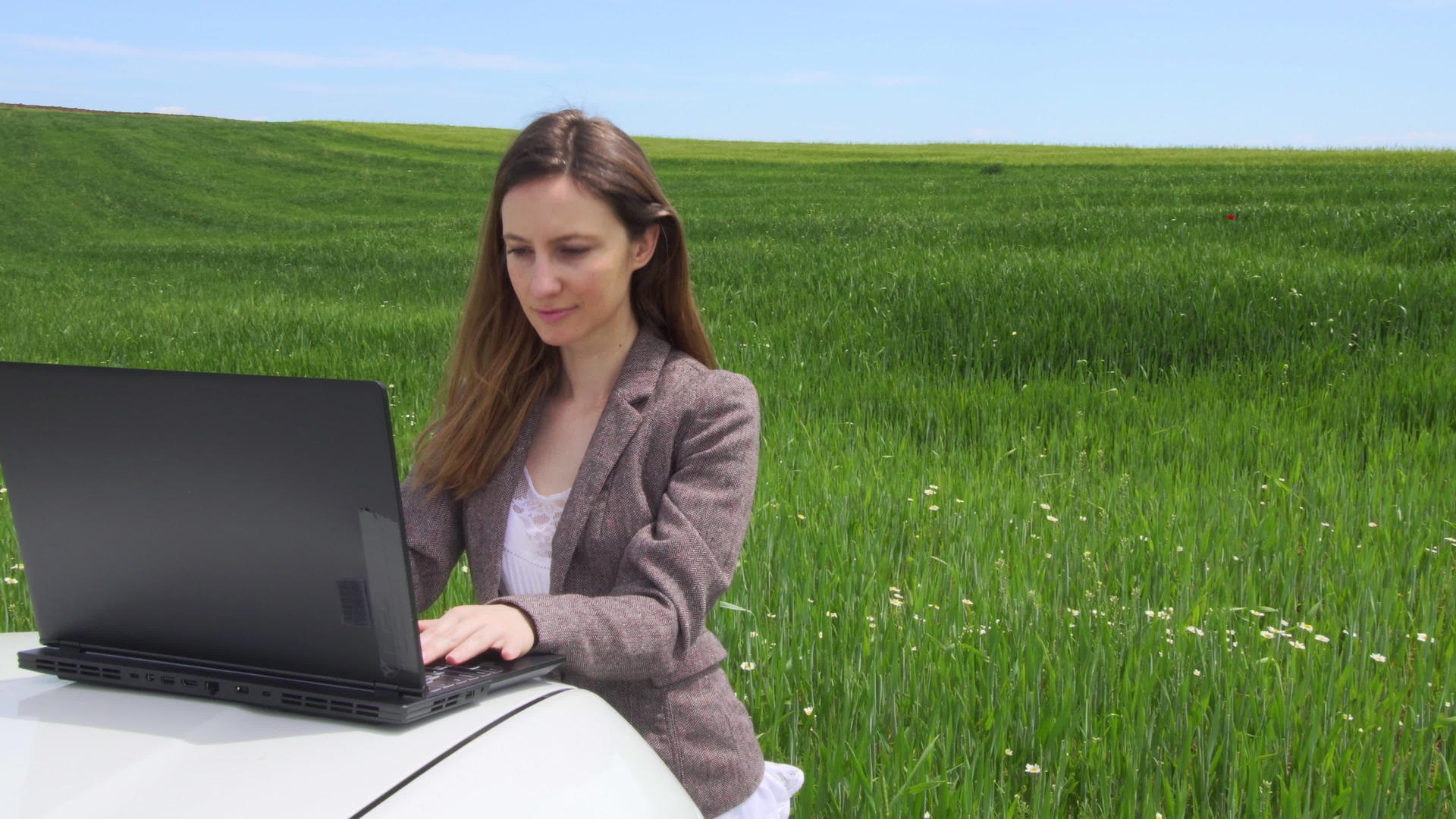 汽车上的笔记本电脑独自在绿色的田野里工作视频的预览图