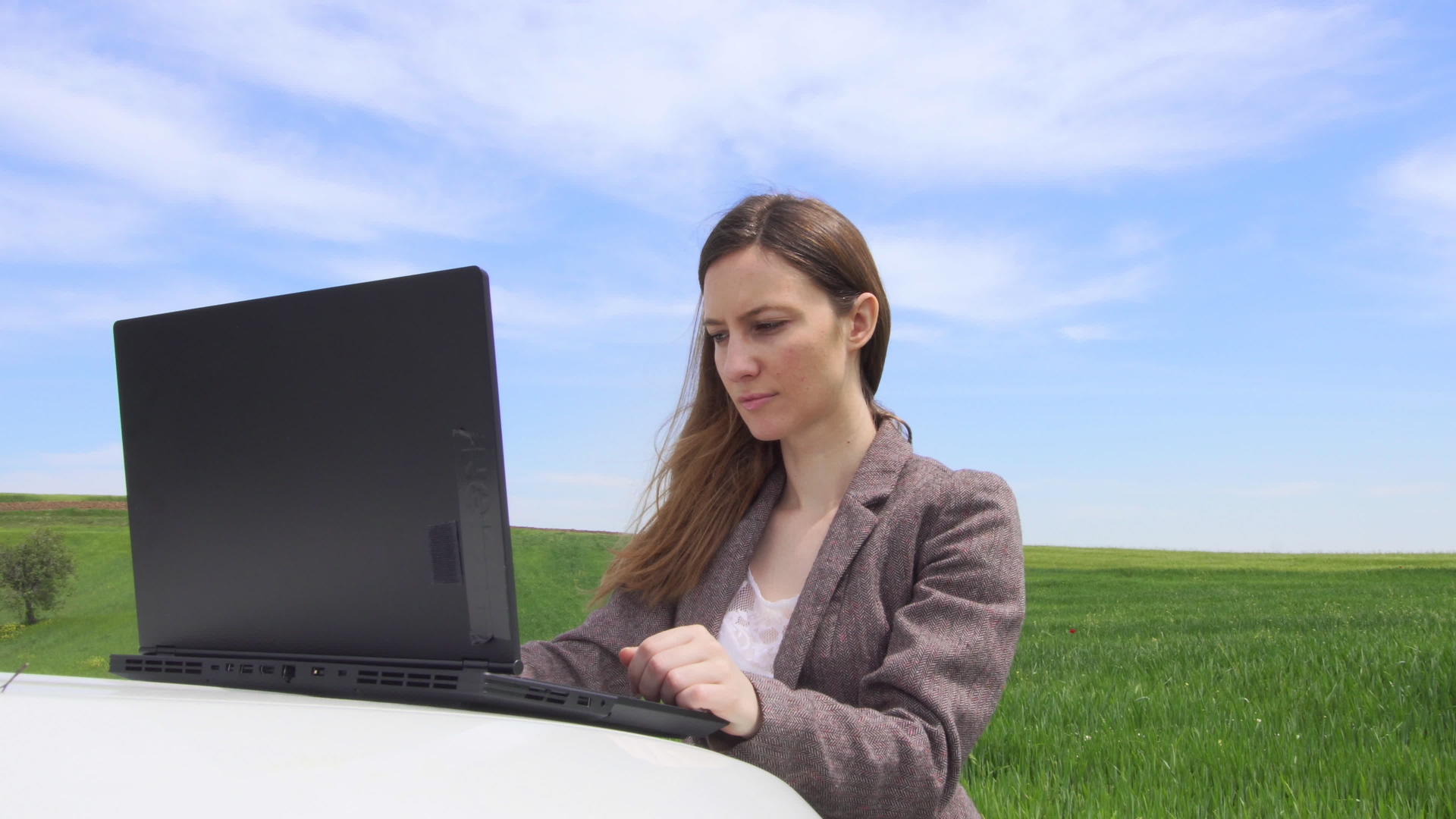 汽车上有一台笔记本电脑独自在绿色的田野里自由商业视频的预览图