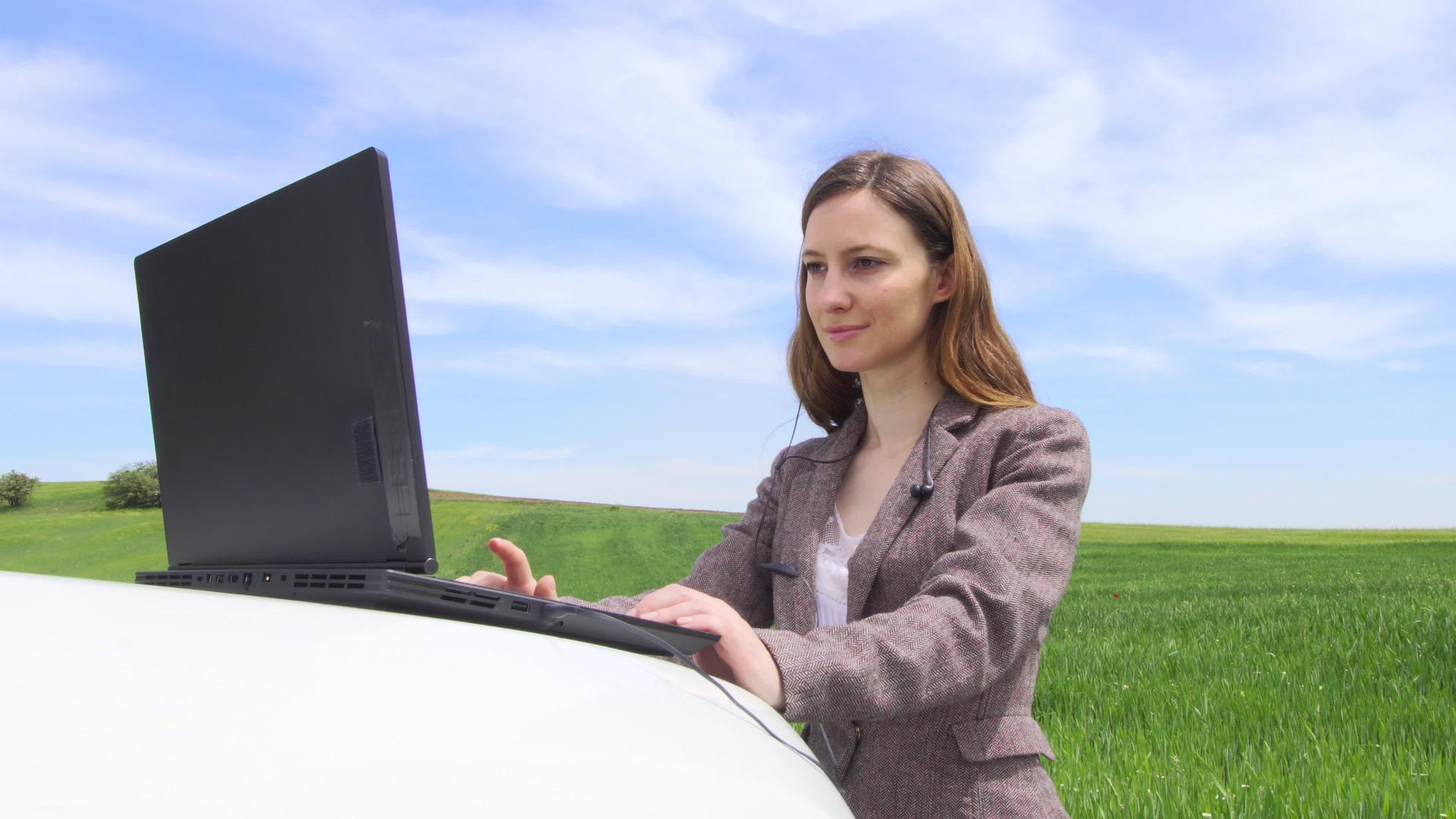 女商人在车上的笔记本电脑上工作戴上耳机参加电话会议视频的预览图