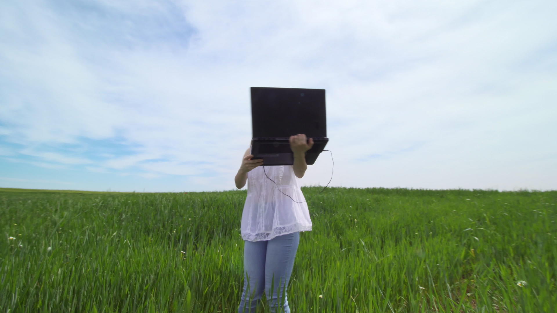 女孩独自在绿色领域使用笔记本电脑视频的预览图