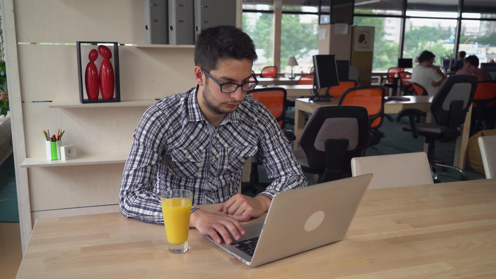 英俊的男人用笔记本电脑工作喝橙汁视频的预览图