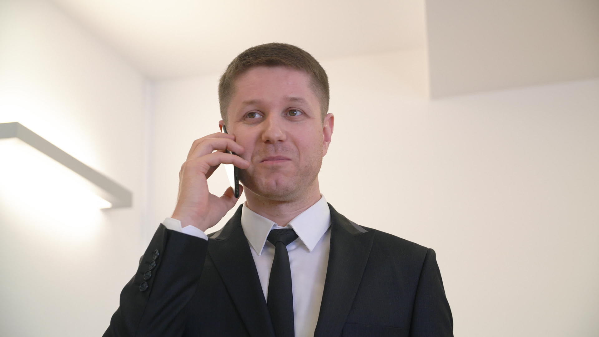 穿着西装打领带的帅帅商人在办公室打电话视频的预览图