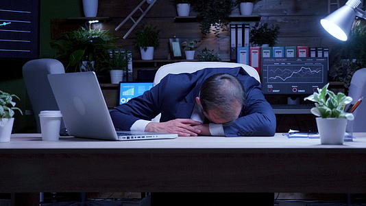 工作过度的商人晚上在办公室睡觉视频的预览图