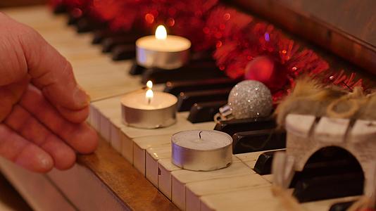 用圣诞装饰的钢琴男人的手在圣诞蜡烛背景中点亮圣诞花环视频的预览图