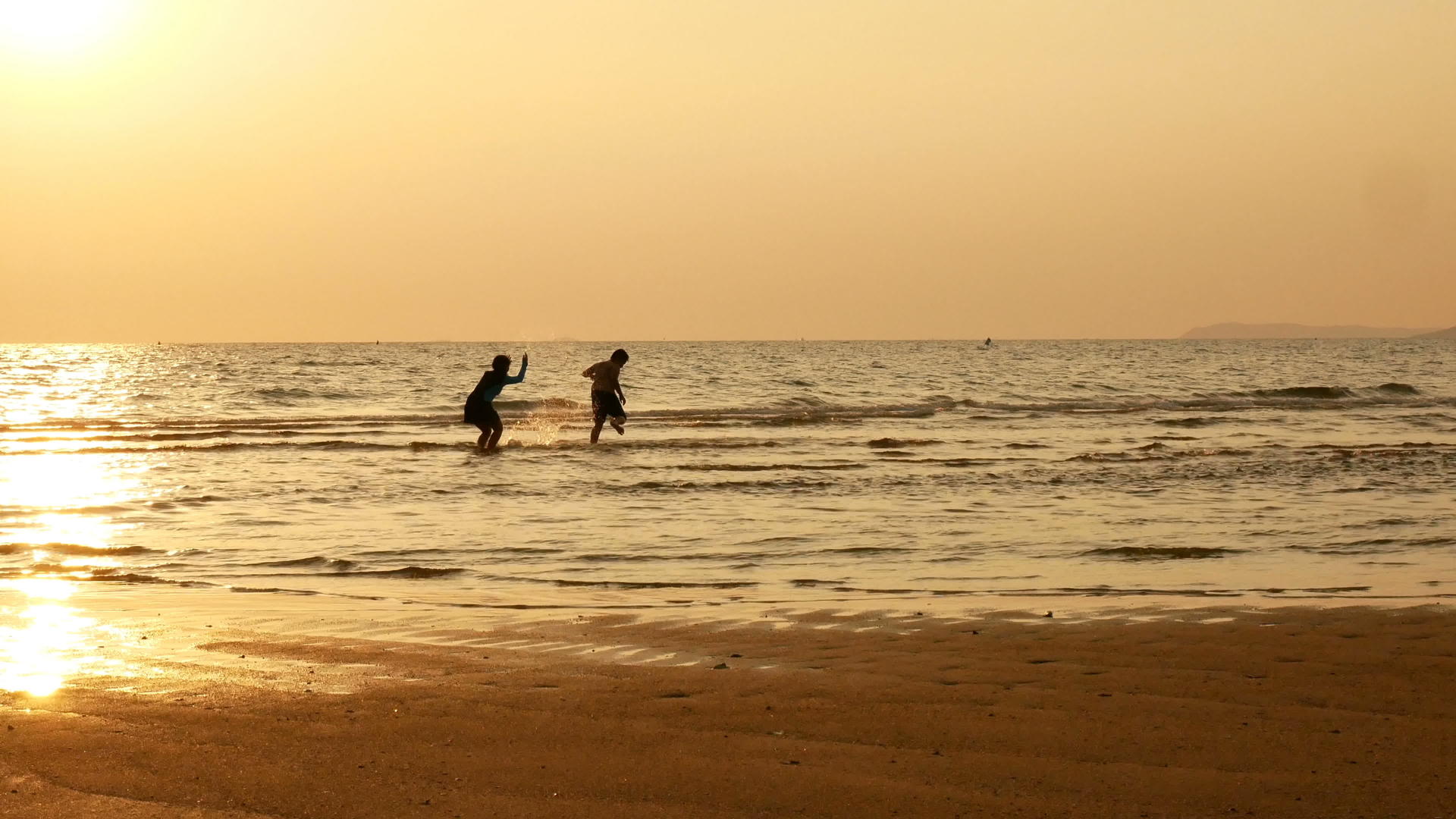 日落时分姐姐和哥哥在海滩上奔跑和玩水视频的预览图