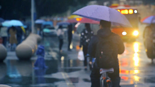 雨天大街上打伞骑自行车的路人视频的预览图