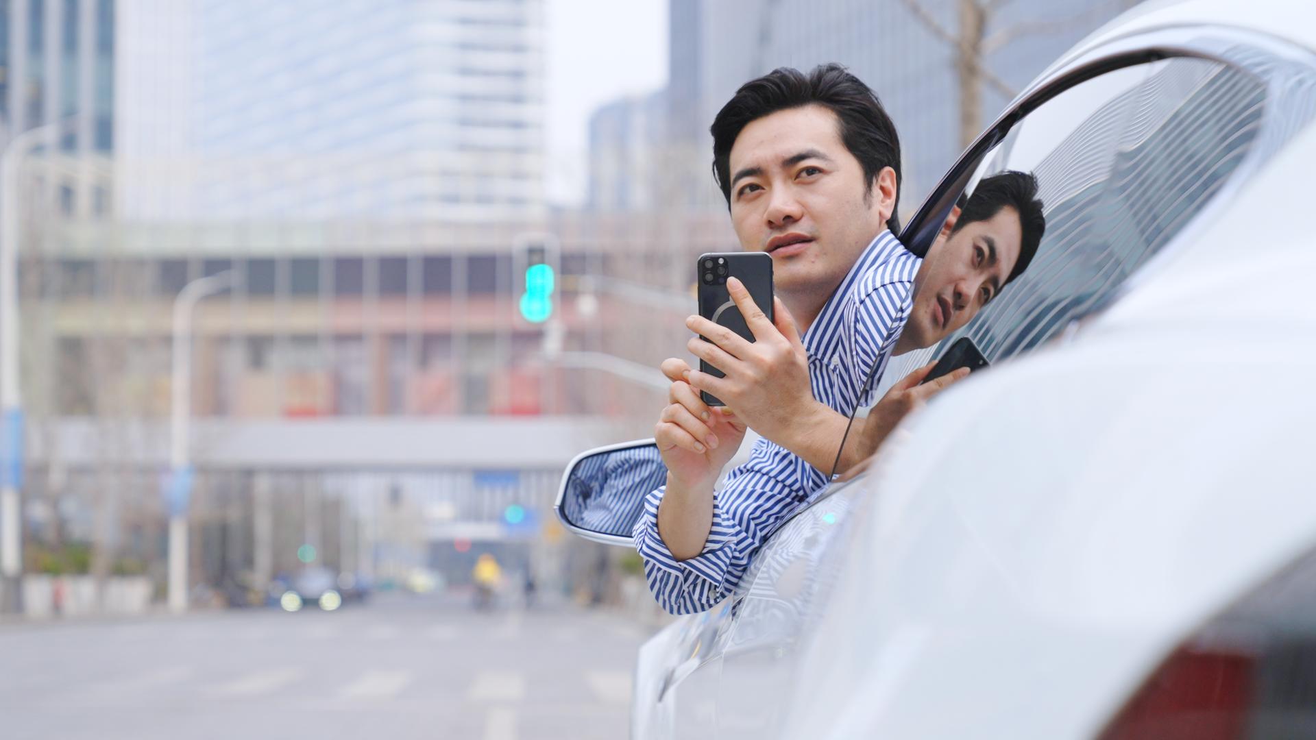 男子将身子探出车窗用手机拍摄视频的预览图
