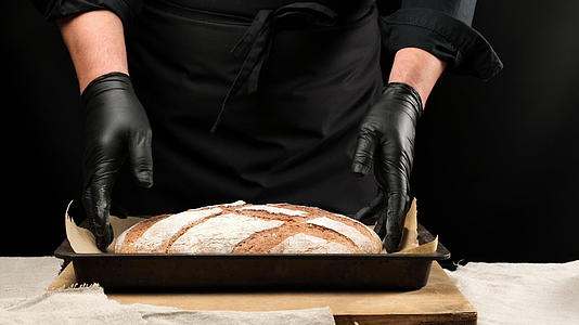 厨师戴着黑色乳胶手套把烤黑麦面包放在烤盘上视频的预览图