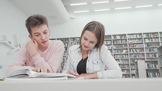 两个大学生朋友在图书馆一起学习的低角镜头照片来自图书馆视频的预览图