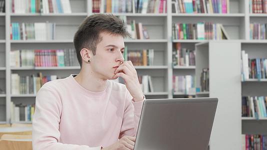 当年轻人在图书馆做笔记本电脑时他们看着体贴的年轻人视频的预览图