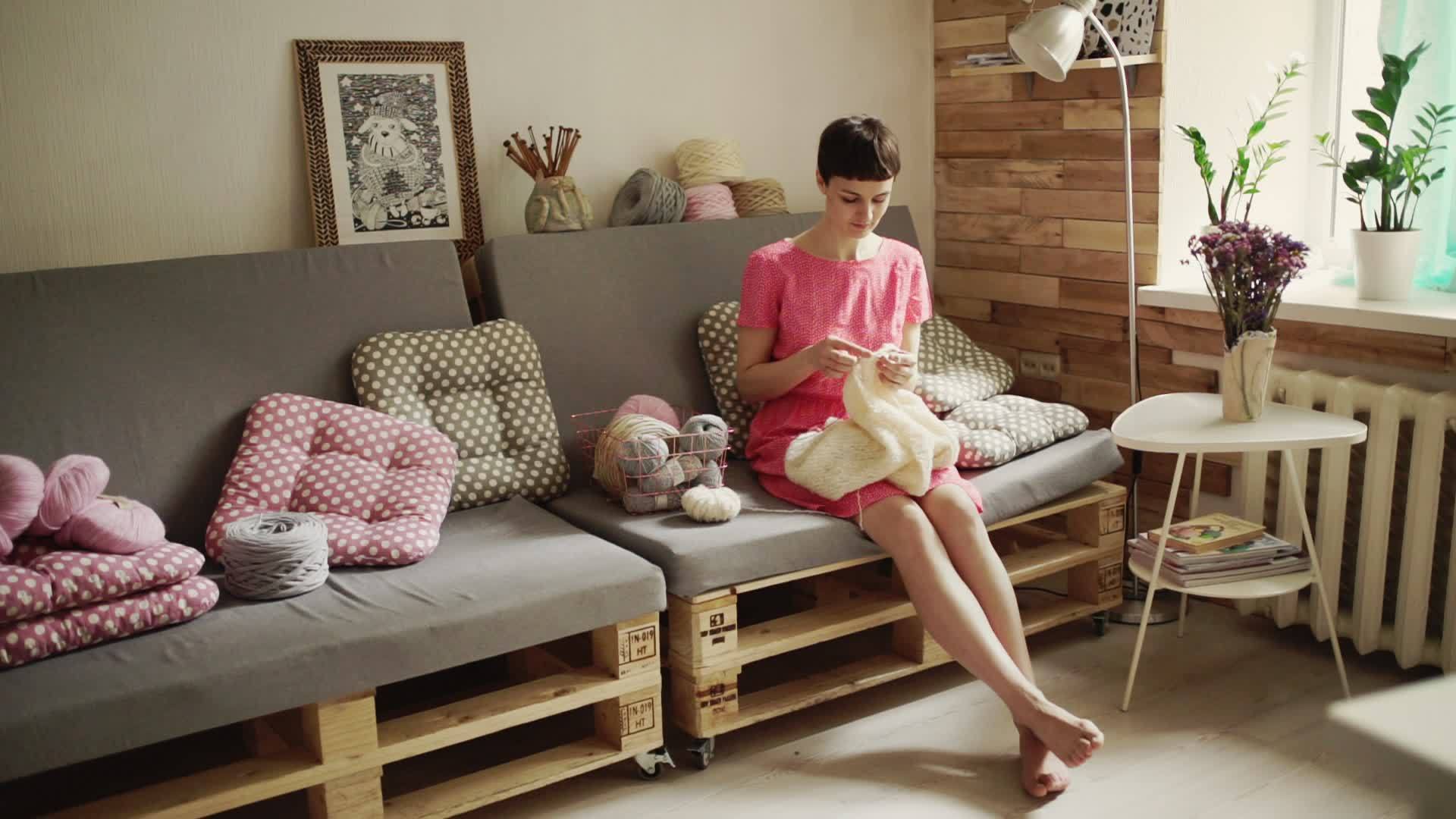 白发女人坐在沙发上织毛衣的时尚爱好视频的预览图