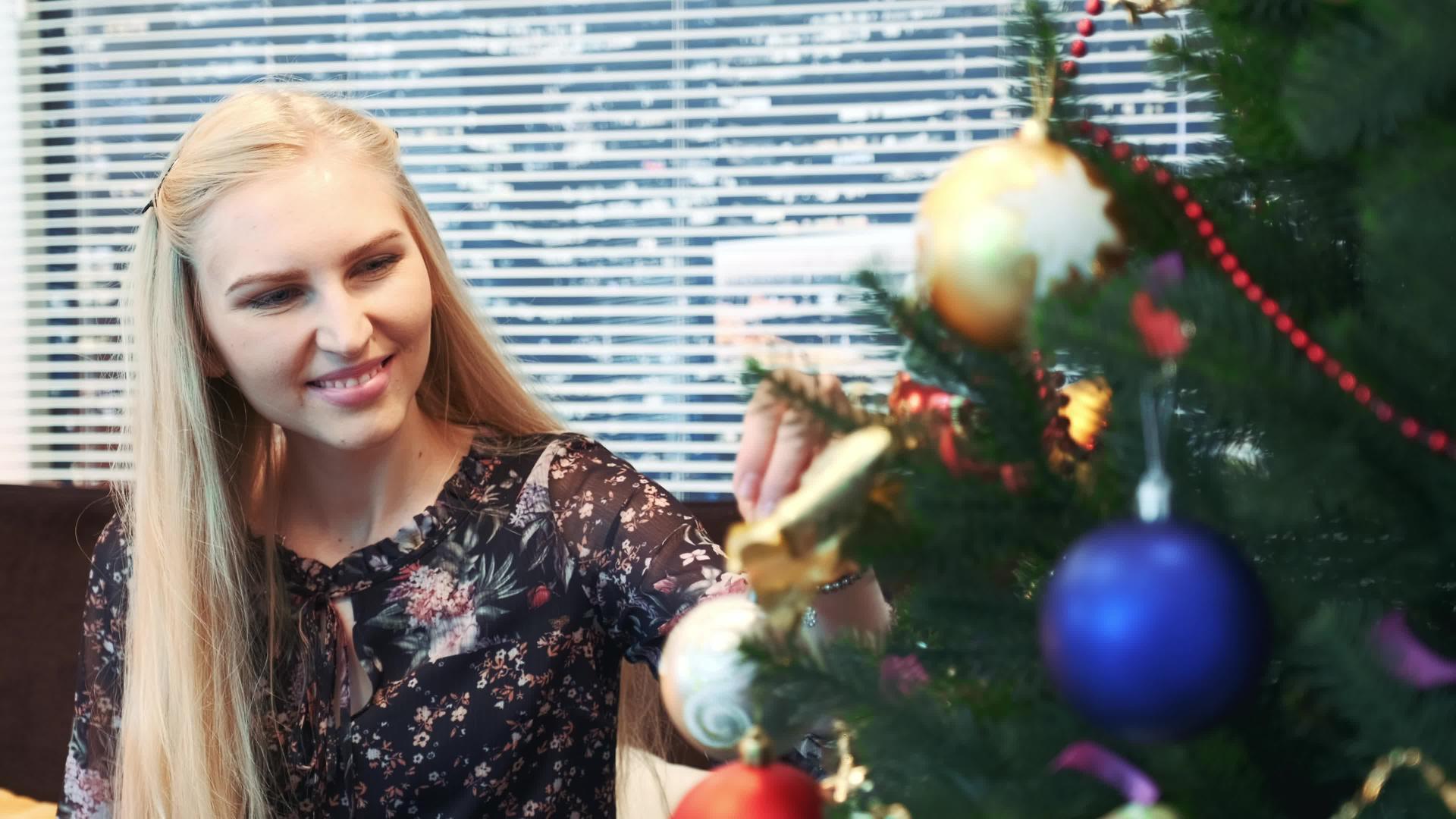 微笑的女孩把球挂在圣诞树上视频的预览图