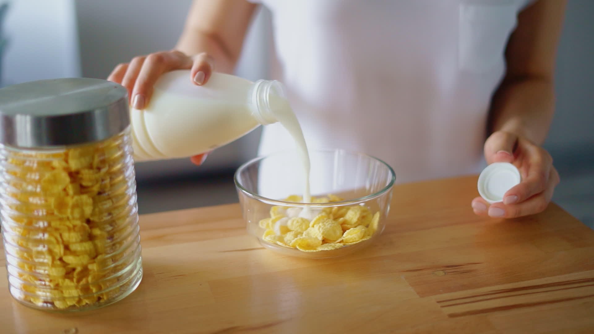 妇女双手将牛奶倒入玉米片玻璃碗中视频的预览图