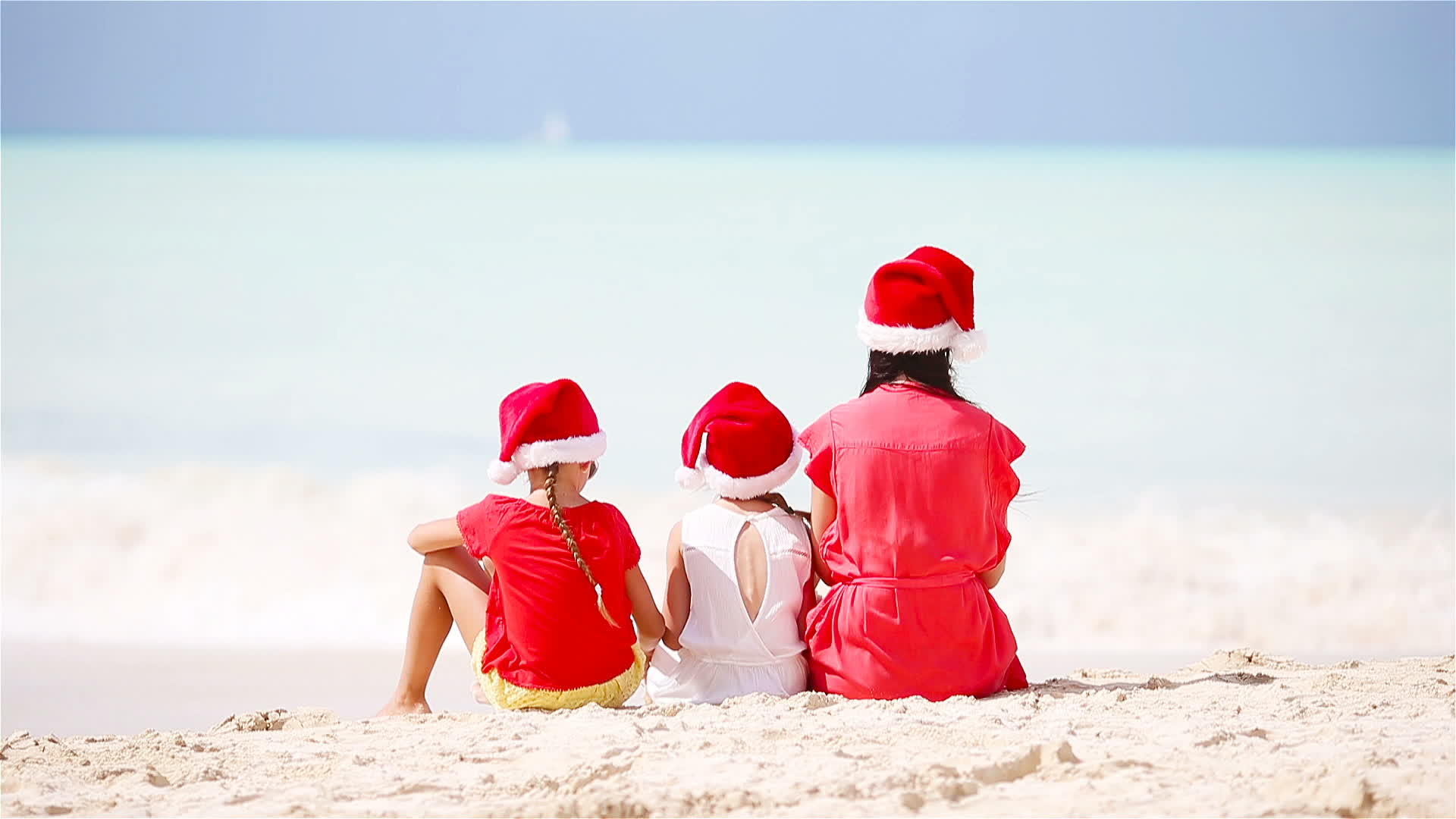 母亲和女儿在澳大利亚白色圣诞海滩上戴着红色圣诞帽子视频的预览图