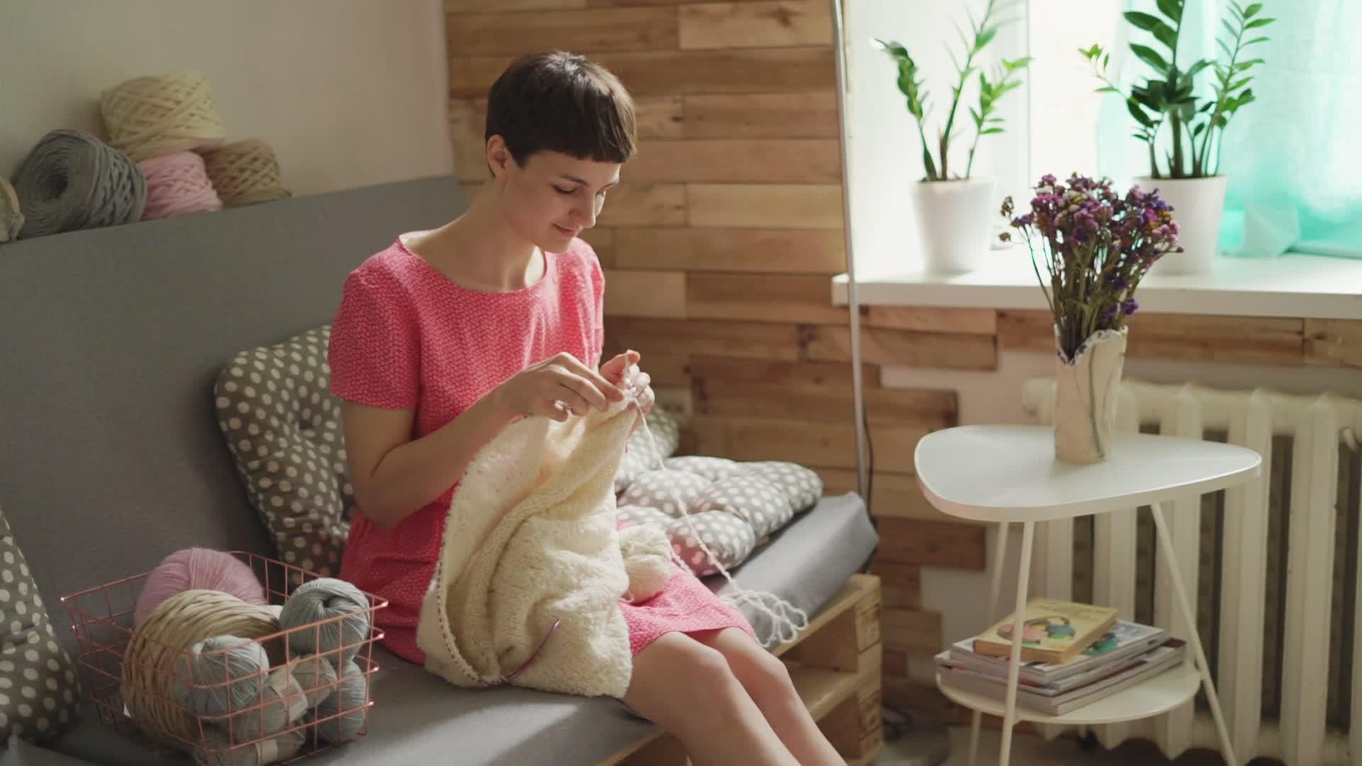 女青年在舒适房间的沙发上织毛衣视频的预览图