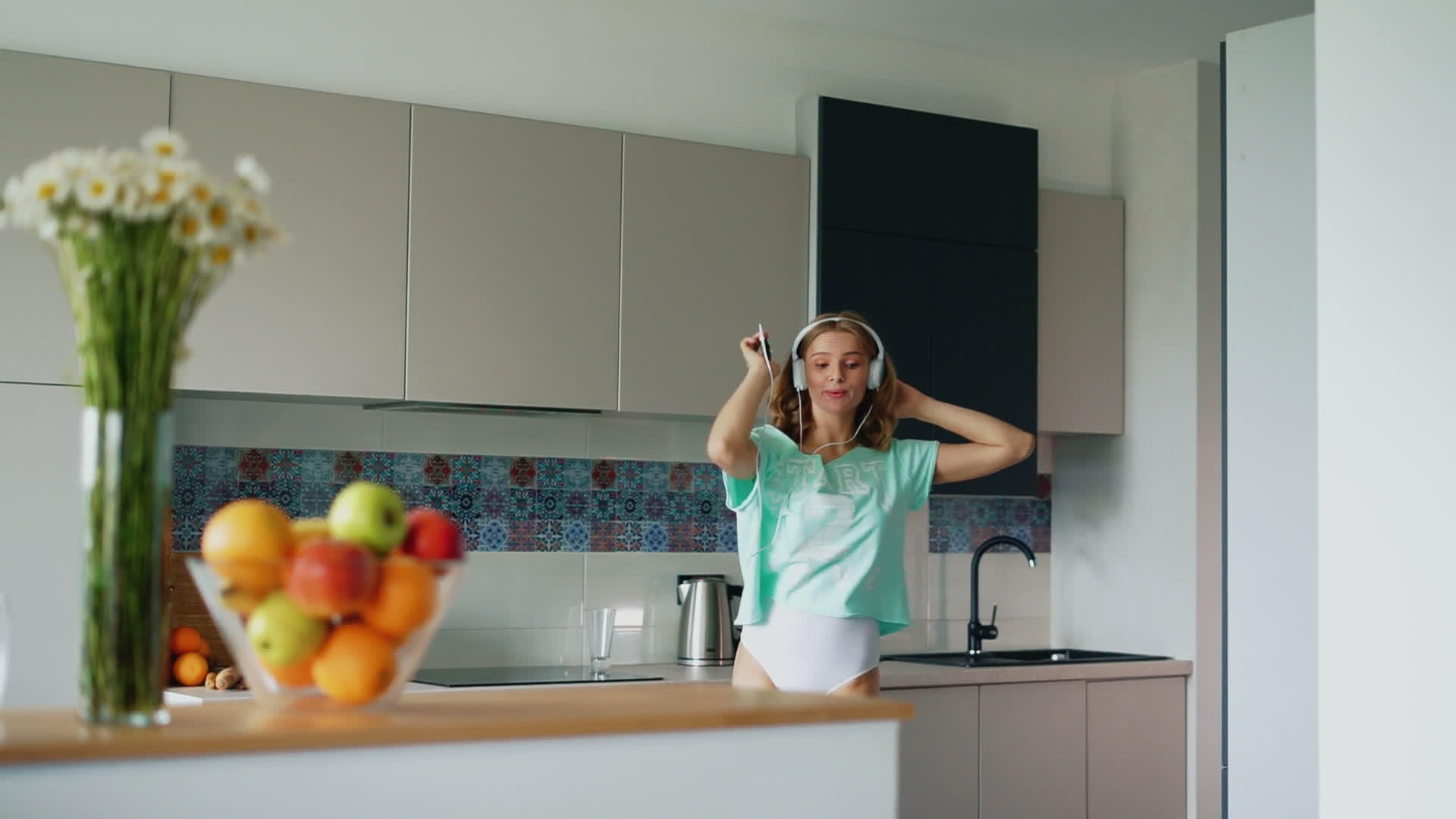 厨房里穿着T恤的性感女孩唱歌跳舞视频的预览图