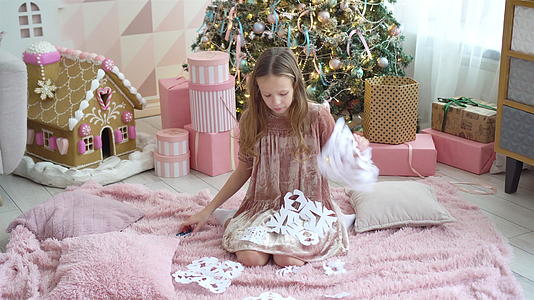 可爱的小女孩坐在树旁做雪花纸的房间装饰得满地都是视频的预览图