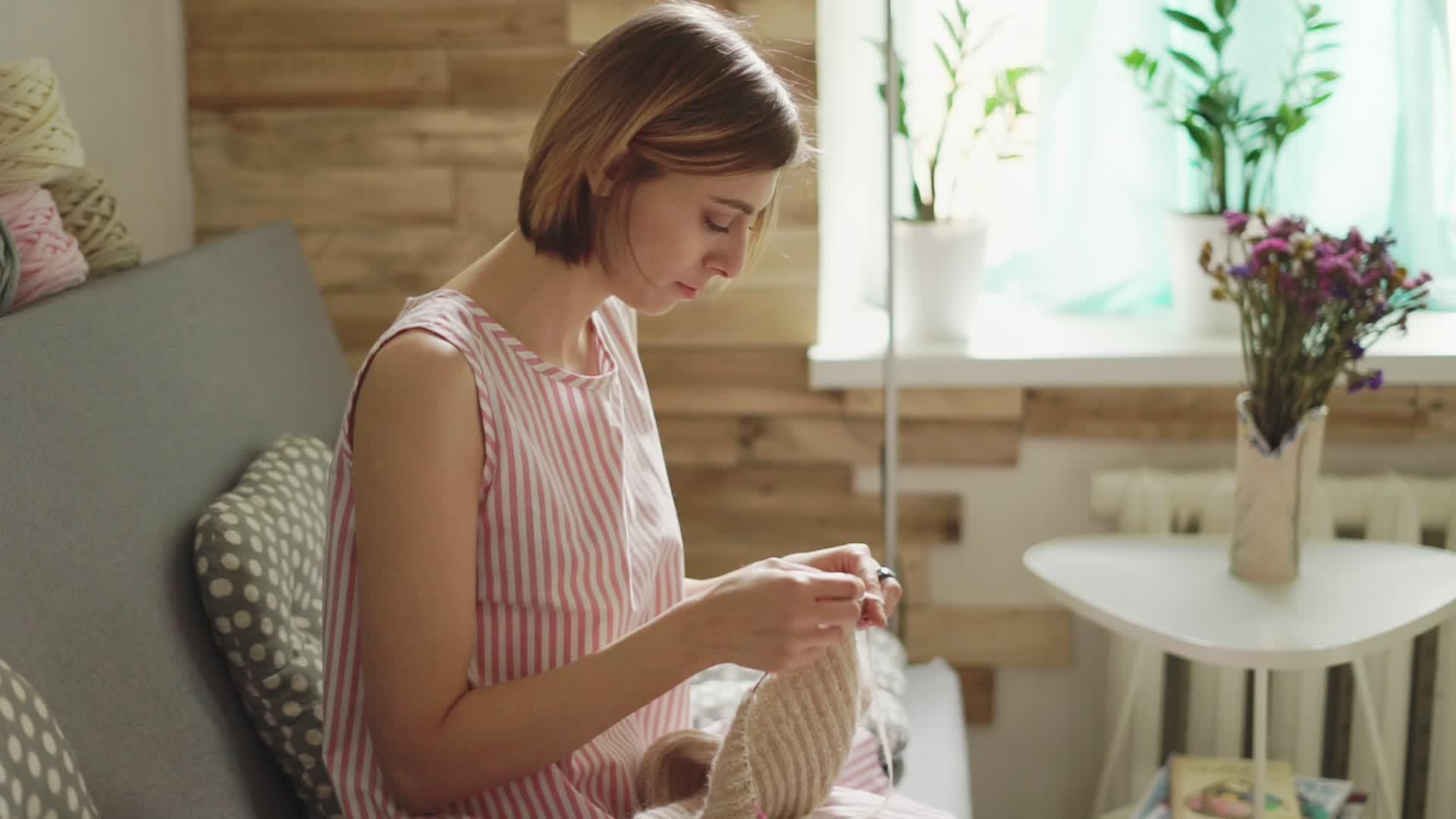 手工艺品女性坐在后窗和毛巾上的沙发上视频的预览图