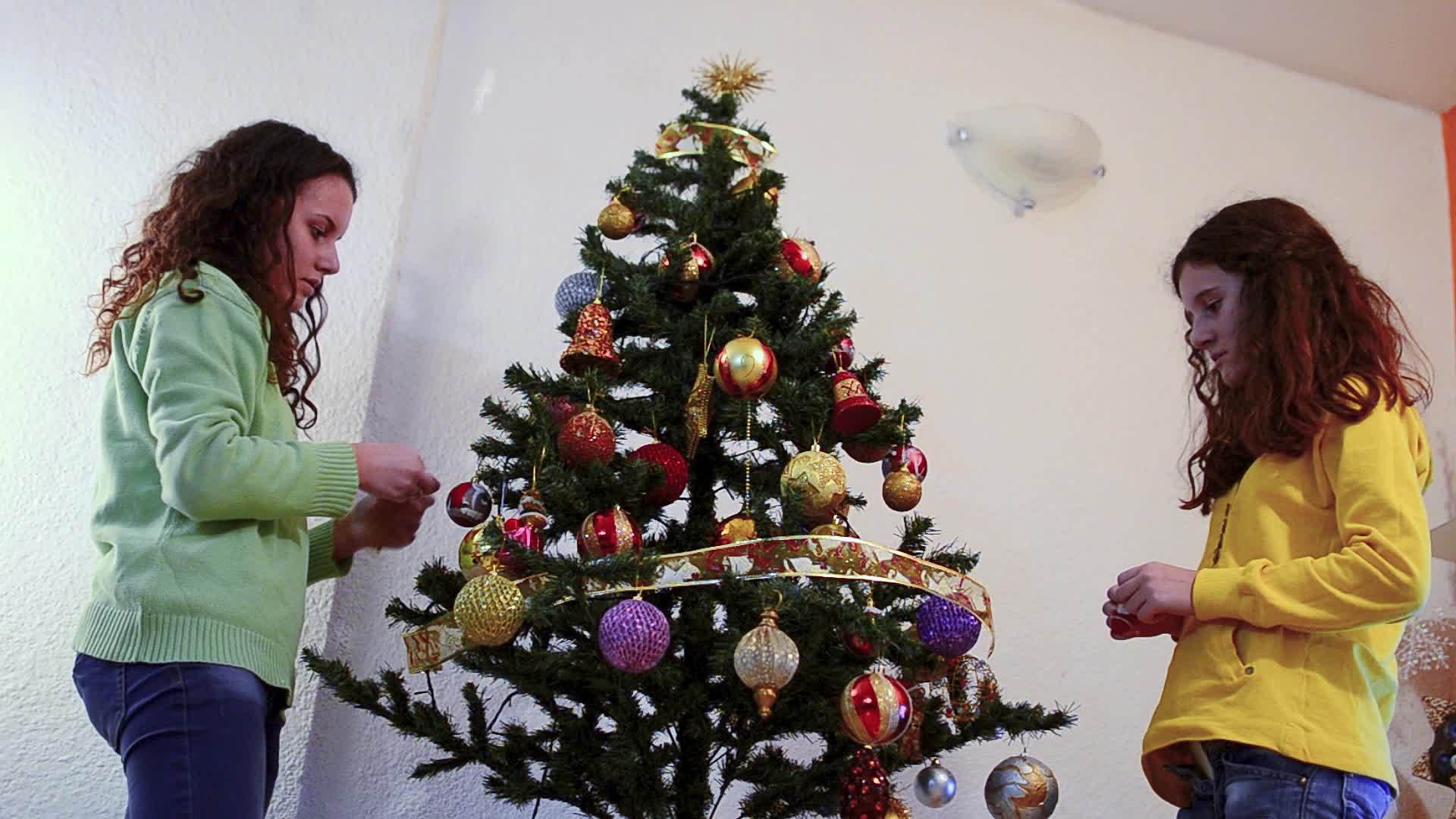 快乐的青少年在节假日与圣诞灯相邻xmas树边玩视频的预览图