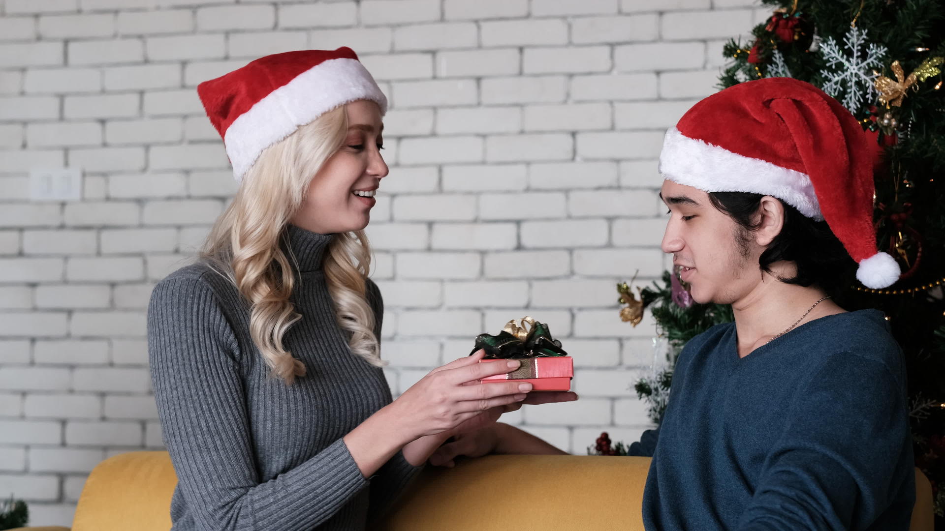 一个年轻漂亮的女人在圣诞树的房间里给她的年轻男友圣诞礼物视频的预览图