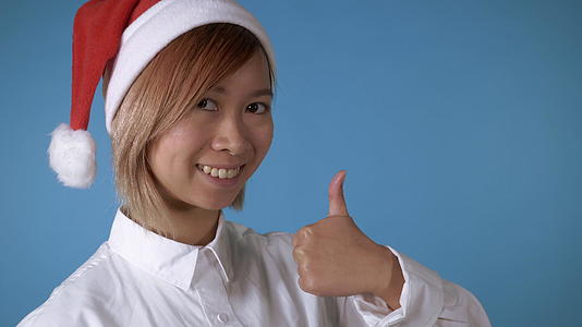美丽的女孩的圣诞礼帽露出了她的拇指视频的预览图