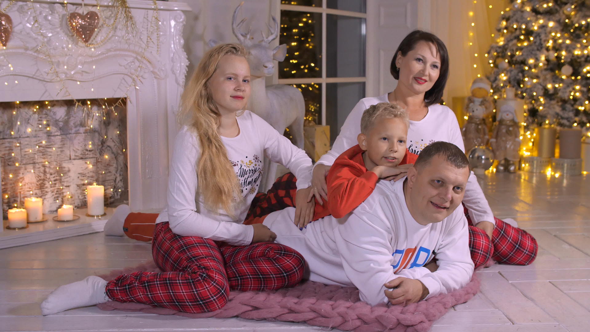 亲生父母、女儿和儿子在圣诞树和壁炉的背景下视频的预览图