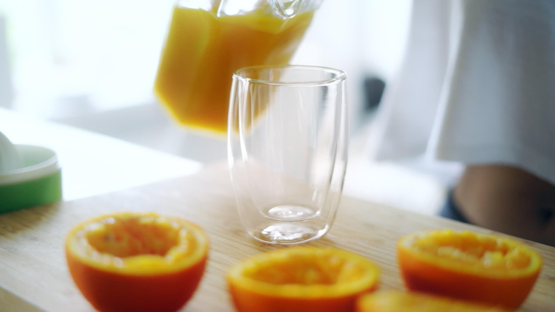将新鲜橙汁从玻璃罐中倒入杯中挤压橙汁视频的预览图