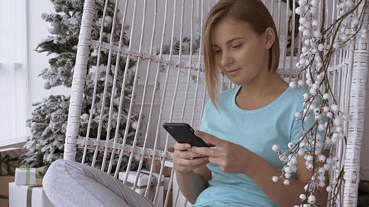 在装饰冬季节日的家里给快乐女孩发短信视频的预览图