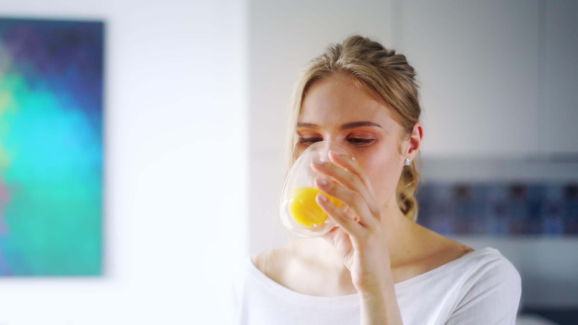 美丽的女孩在杯子上喝鲜橙汁视频的预览图