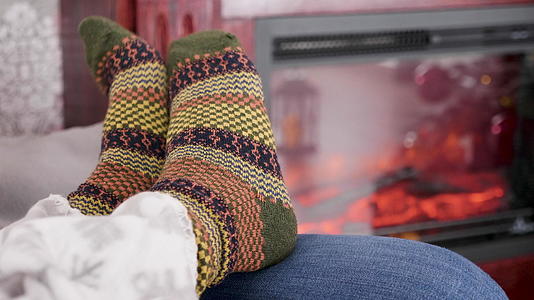 女人的脚在燃烧的壁炉旁边穿着温暖的羊绒袜子视频的预览图