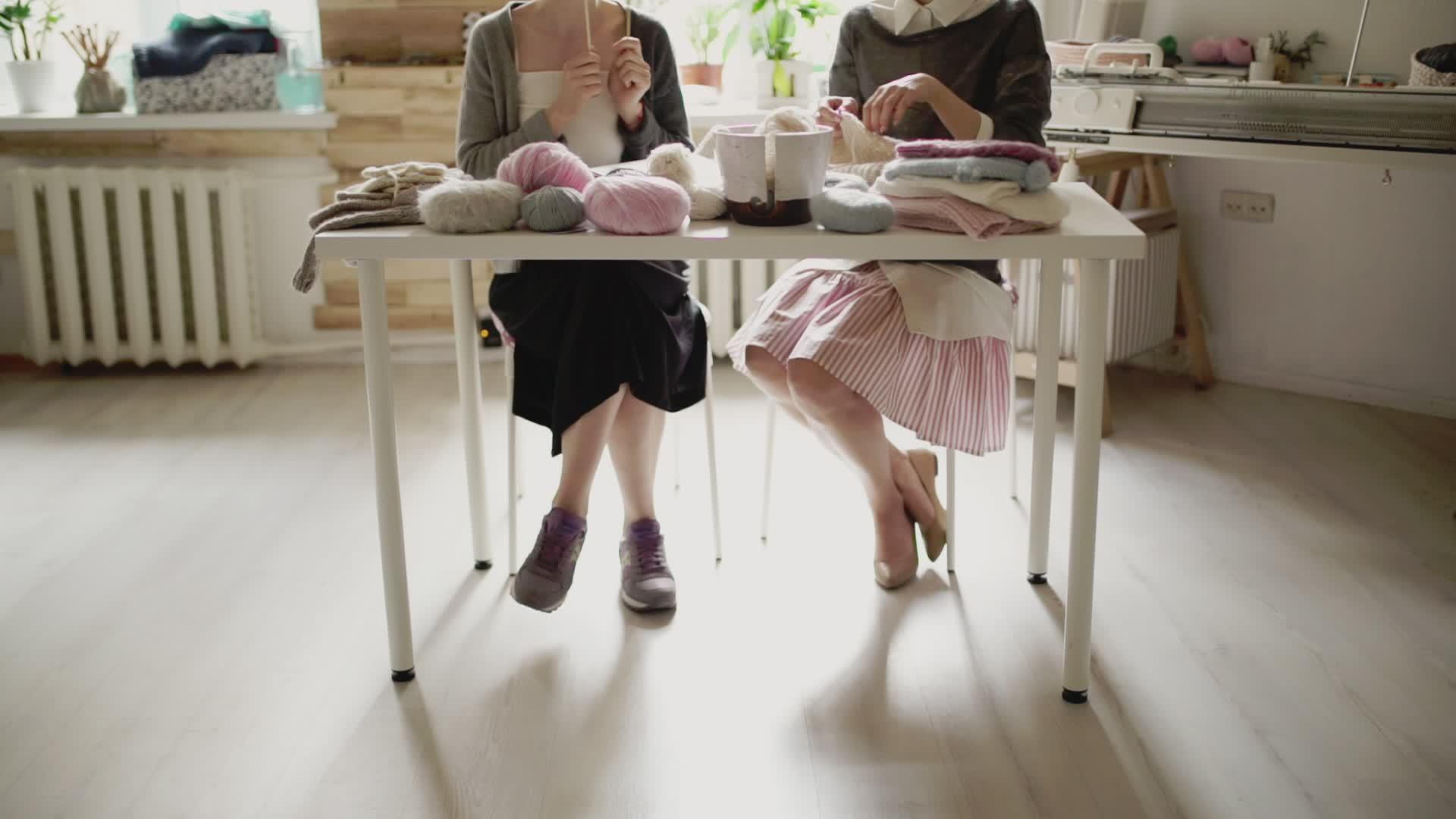 女用腿坐在桌边编织针头视频的预览图