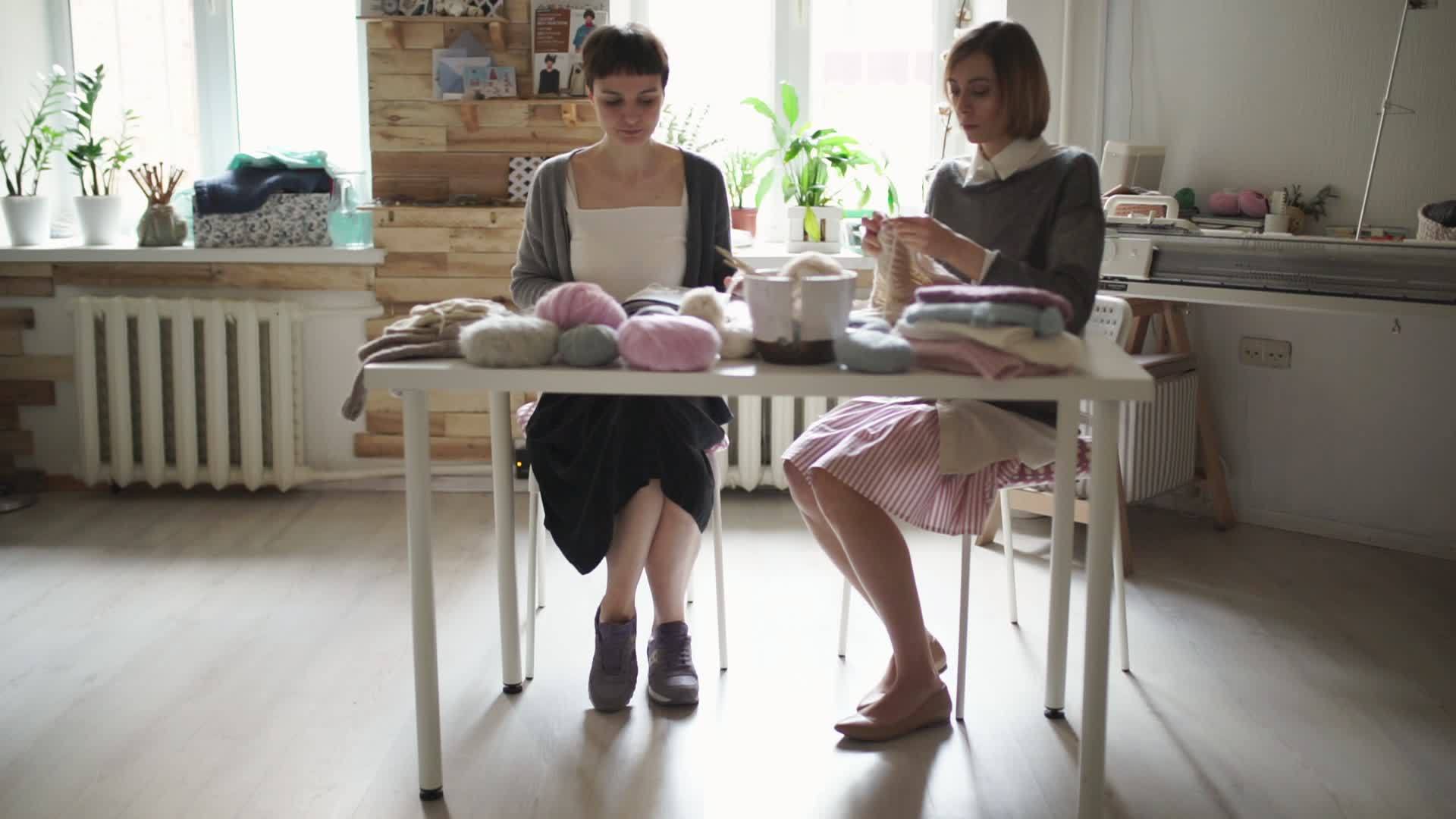 两名编织妇女坐在桌子旁在纺织车间做羊毛布视频的预览图