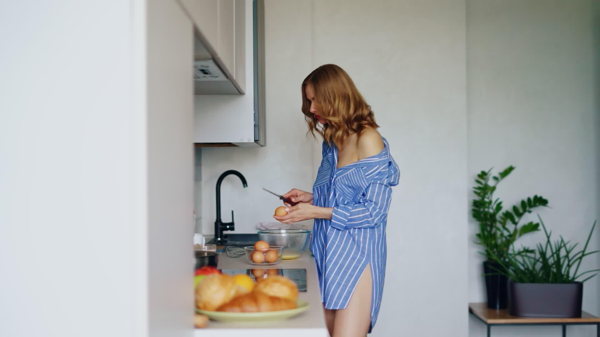 一个穿着衬衫的性感女孩把鸡蛋打成了厨房的玻璃碗视频的预览图