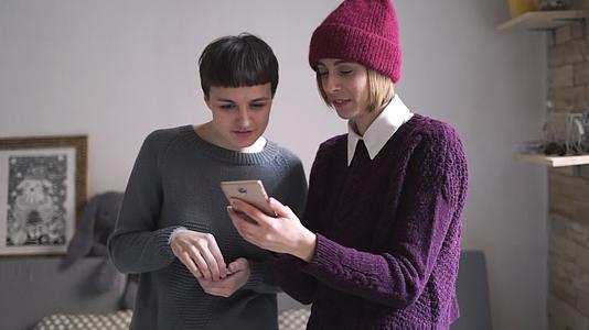 两个年轻女子在房间里看手机视频的预览图