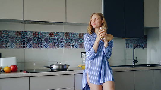 一个穿着睡衣的性感女孩喝杯子里的橙汁女孩享受水果视频的预览图