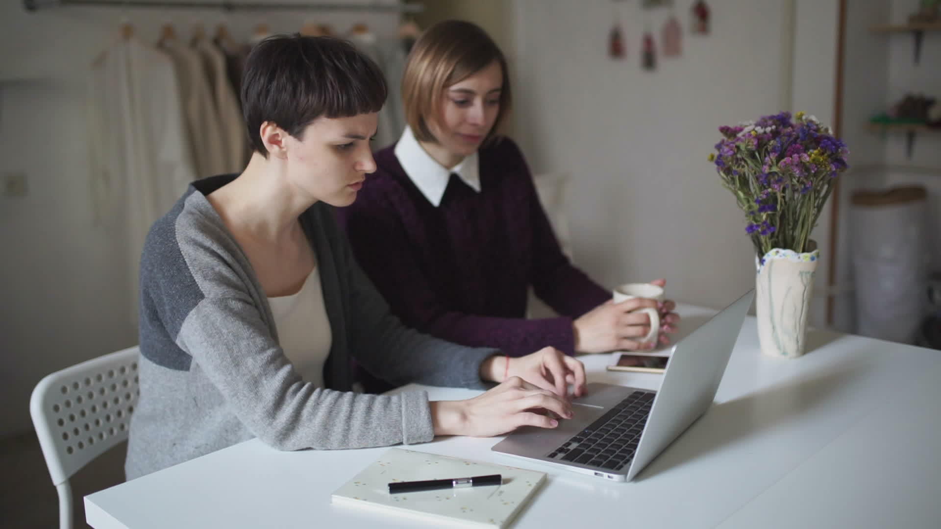 两名年轻女子在家里用笔记本电脑坐在桌旁视频的预览图