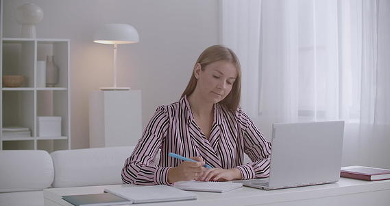 年轻女性在家在线学习课程中观看笔记本电脑的展示和展示视频的预览图