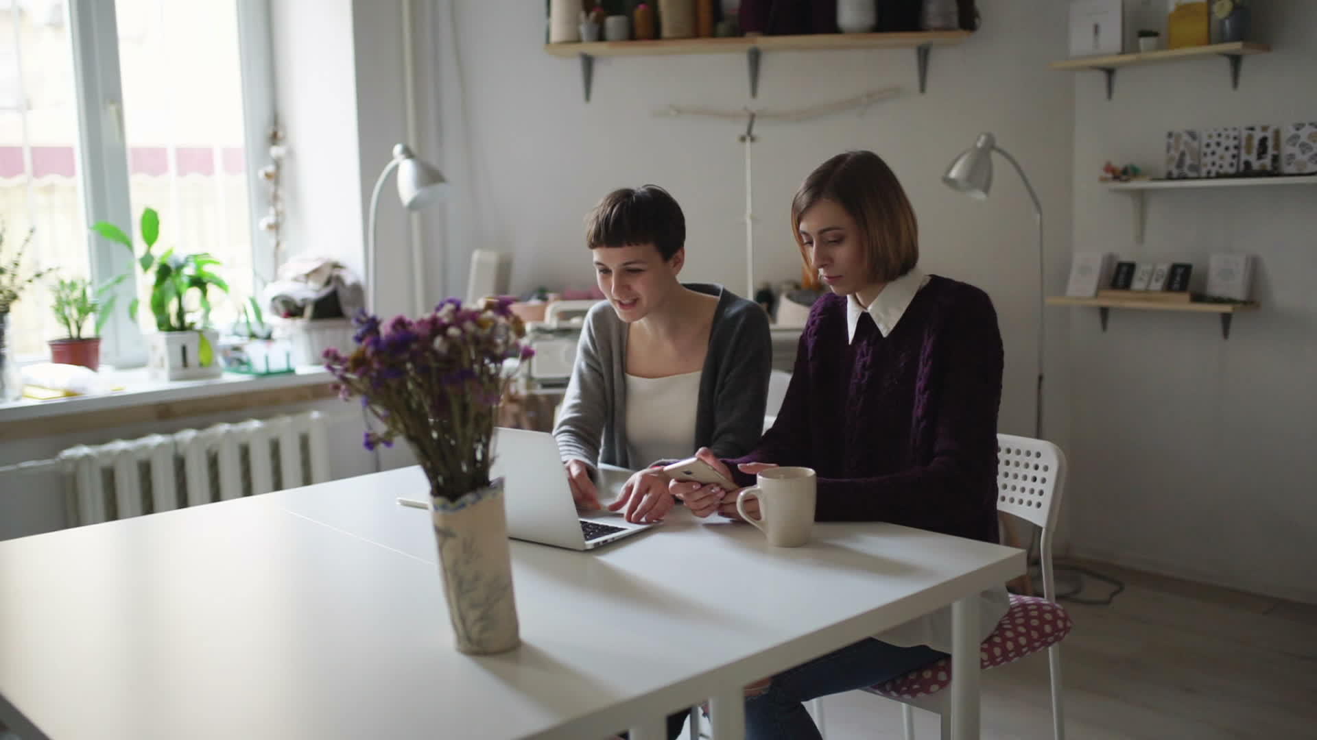 桌边的两名女学生用笔记本在家中线学习视频的预览图