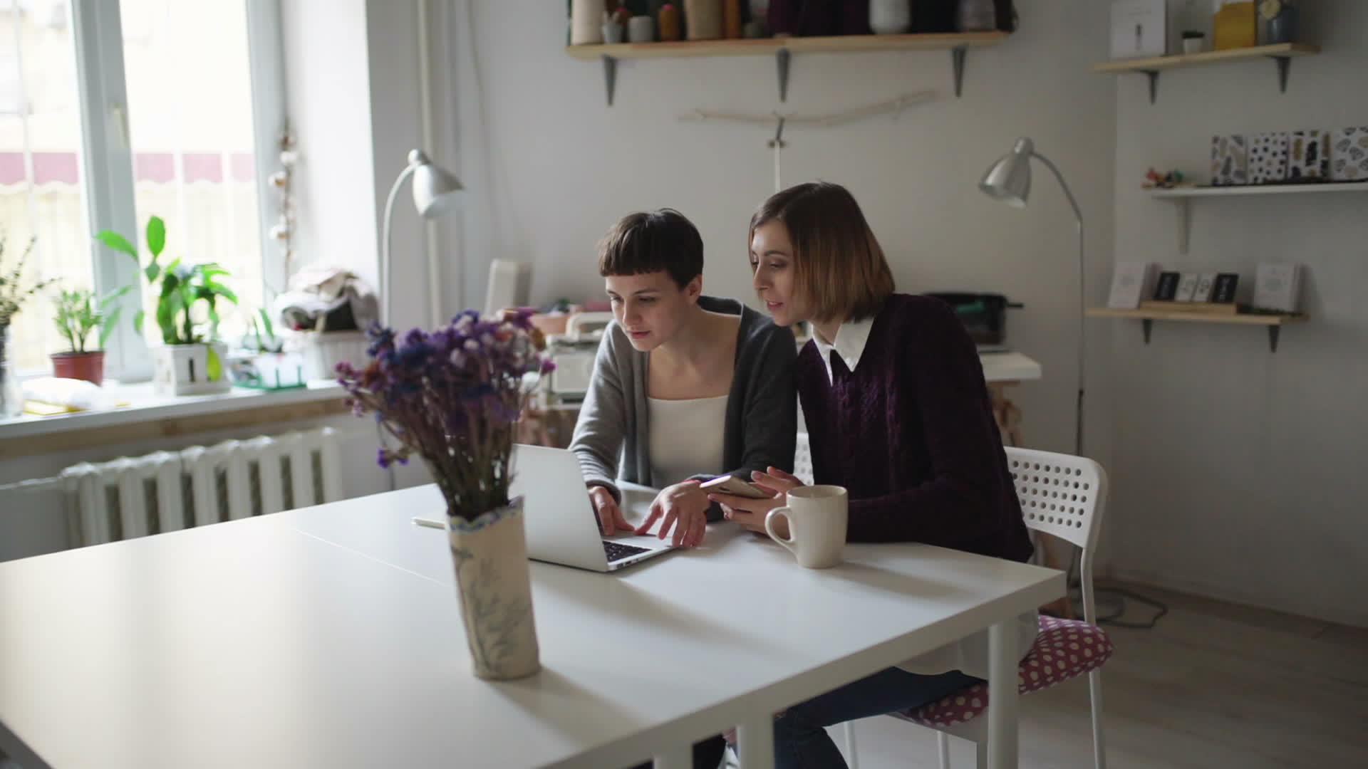 闲暇时两个女朋友用笔记本坐在桌旁视频的预览图