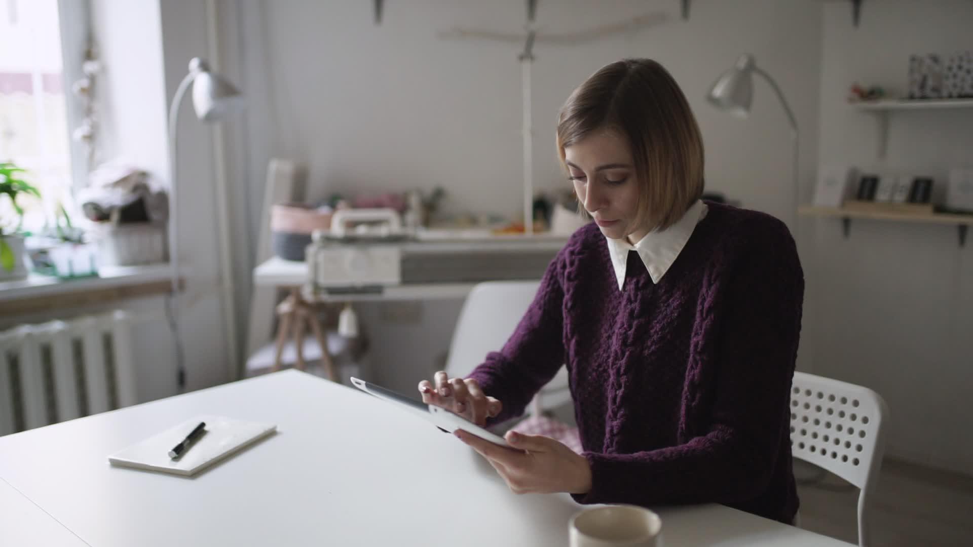 年轻女性用平板电脑坐在家里的桌子上视频的预览图