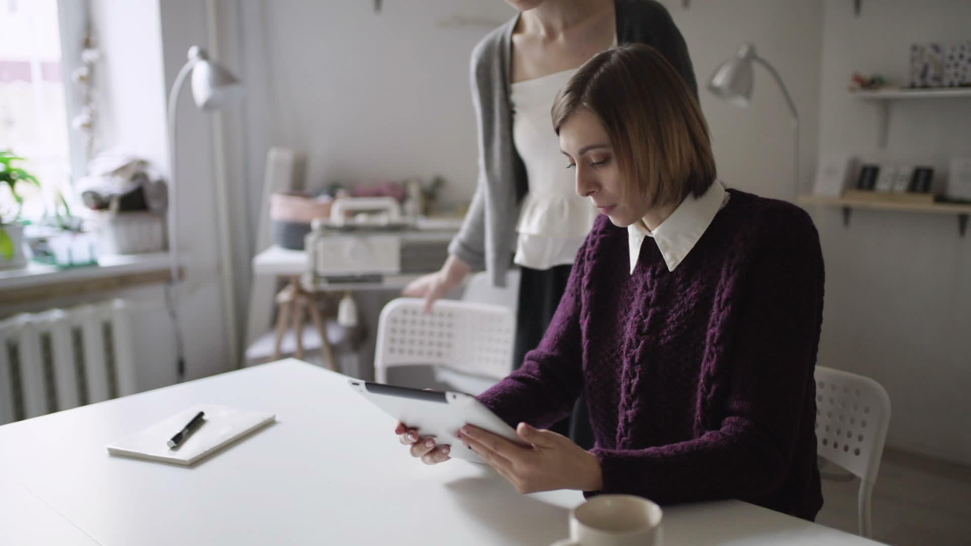 年轻女性坐在桌边用平板电脑和朋友坐在一起视频的预览图